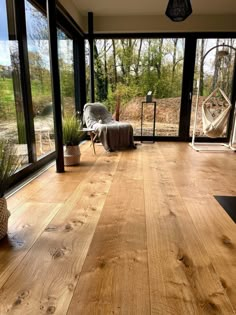 an empty room with wooden floors and glass doors leading to a deck area that has a hammock chair on it