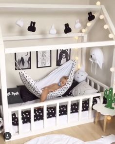 a baby is laying in a white crib with black and white decorations on the walls