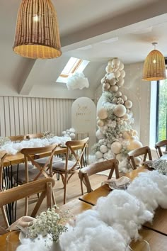 a room filled with lots of tables and chairs covered in fluffy white stuff next to a tall christmas tree