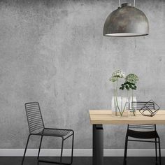 two chairs and a table with vases on it in front of a concrete wall