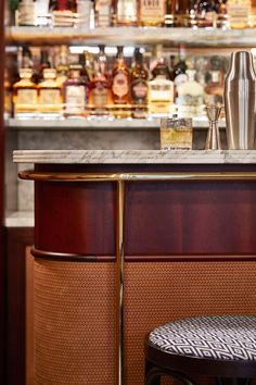 a bar with liquor bottles behind it and a stool next to it in front of the bar