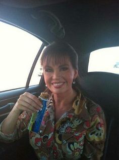 a woman sitting in the back seat of a car holding up a package of toothpaste