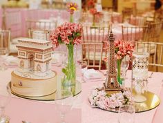 the table is set up with pink flowers and vases on top of each other