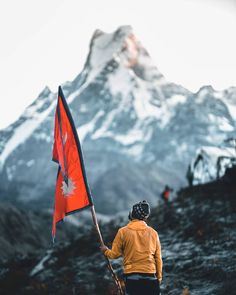 a man holding a canadian flag on top of a mountain