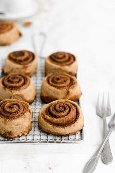 several cinnamon rolls on a cooling rack with forks