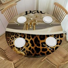 an animal print table cloth with white plates and silverware on it in front of a dining room set for four