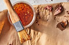 a wooden spatula filled with sauce on top of a piece of paper next to other items