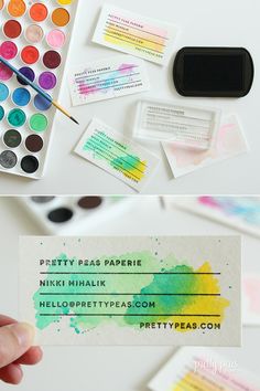 the business card is being painted with watercolors and inkspots on it