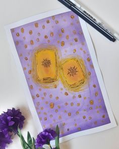 two yellow squares on purple paper next to some flowers and a marker with a pen