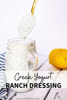 a glass jar filled with ranch dressing next to a lemon on a white wooden table