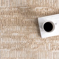 a cup of coffee sitting on top of a carpeted floor next to a rug