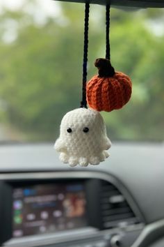 two crocheted decorations hanging from the dashboard of a car