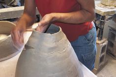 a woman is making a vase out of clay