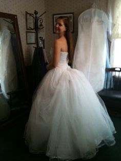 a woman in a white wedding dress standing next to a mirror