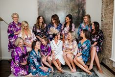 a group of women sitting next to each other in matching purple and blue robes on top of a rug