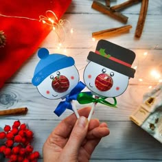 two snowmen holding candy lollipops in their hands on a wooden table