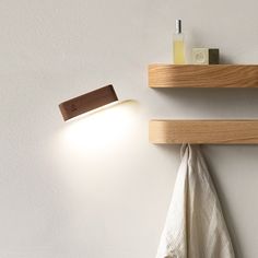 two wooden shelves with towels hanging from them and a light on the wall next to it