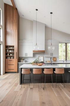 a large kitchen with wooden floors and white cabinetry on the walls, along with four bar stools