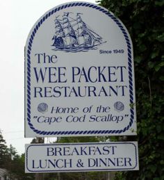 a sign for the wee packet restaurant and cafe co - op scallop in front of some trees