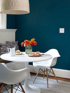 a dining room with blue walls and white chairs