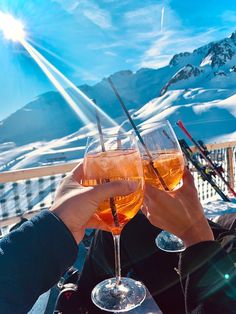 two people toasting wine glasses with skis in the background