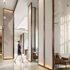 a woman walking through an office lobby with white walls and wood trimmings on the doors