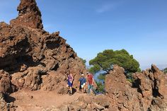 three people standing on top of a rocky mountain