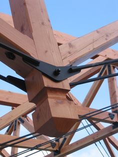 a wooden structure with metal straps attached to the top and bottom beams, against a blue sky