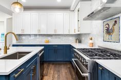 a kitchen with blue and white cabinets, marble counter tops, gold accents and brass fixtures