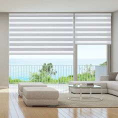 a living room with white furniture and large windows overlooking the ocean on a sunny day