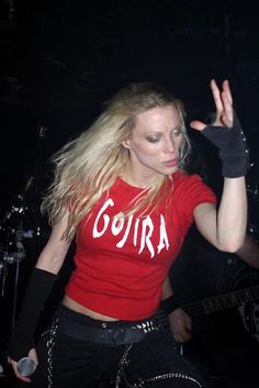 a woman in red shirt and black pants on stage