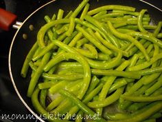 green beans being cooked in a wok on the stove