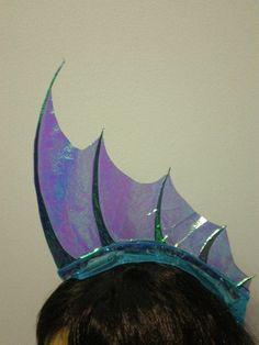 a close up of a person wearing a purple and blue headpiece with leaves on it