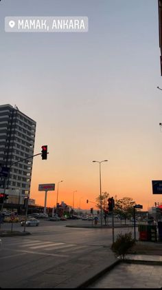 the sun is setting on an empty street with traffic lights and buildings in the background