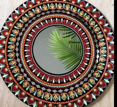 a decorative mirror with a palm leaf in the center