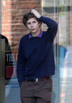 a young man standing in front of a glass door with his hand on his head