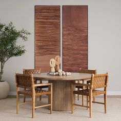 a dining room table with four chairs and a vase on the table next to it