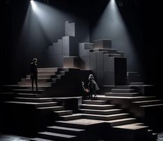 two people are standing on stage in front of some stairs with lights shining down them