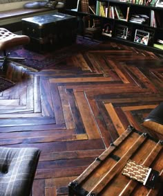 a living room filled with lots of furniture and bookshelves on top of wooden flooring