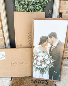 a couple standing next to some boxes on the ground with their wedding photos in them