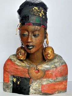 a statue of a woman with her eyes closed and head covered in gold ear rings