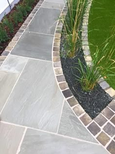 a stone walkway with grass and flowers in the background, along with an artificial lawn