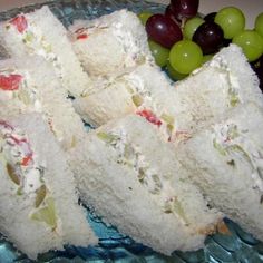 two sandwiches are stacked on a plate with grapes