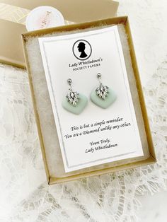 The perfect gift for any Bridgerton fan - a mint blue dangle earring with cubic zirconia accents set with silver findings, inspired by the Diamonds and ladies of the Bridgerton series.  The earrings come packaged from Lady Whistledown herself, with the message that the recipient is a Diamond unlike any other.  Earring components are made from polymer clay with cubic zirconia accents.  Colors and design will vary slightly from those pictured.  Earrings are handmade in small batches.   Your jewelry is always beautifully packaged in a premium kraft brown box, so it is ready for gifting! Check out our full Bridgerton selection here: https://www.etsy.com/shop/hellofriendboutique/?etsrc=sdt&section_id=38227192 Edwina Sharma, Bridgerton Jewelry, Lady Whistledown, Bridgerton Series, Mystery Party, Blue Dangle Earrings, Simple Reminders, Brown Box, Mint Blue