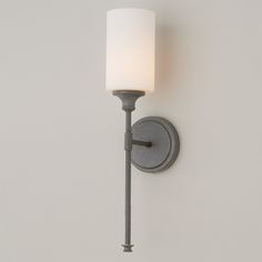 a wall light that is on the side of a wall with a white lamp shade