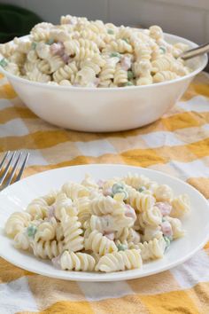 a plate of pasta with peas on it next to a bowl of macaroni and cheese