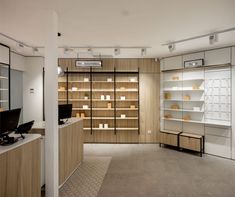 the inside of a store with wooden shelves and glass cases on each wall, along with white shelving