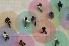 an overhead view of several people walking on a colorful floor with circles painted on it