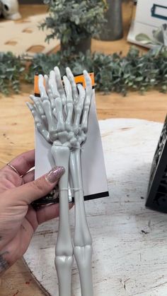 a person holding a fake skeleton fork in front of a piece of paper on top of a table