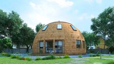 a small round wooden house sitting on top of a lush green field